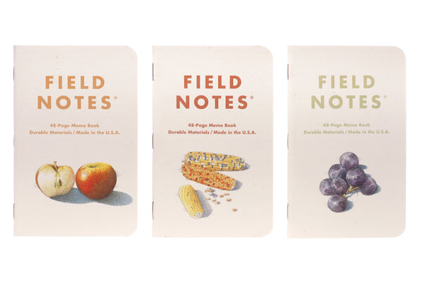 Three Field Notes Harvest notebooks which feature apples, corn, and grapes.