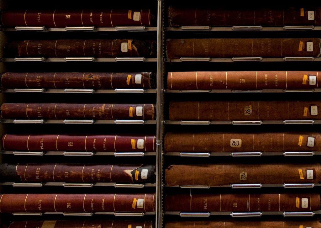 Many volumes are displayed horizontal, one per shelf, on two metal bookcases.