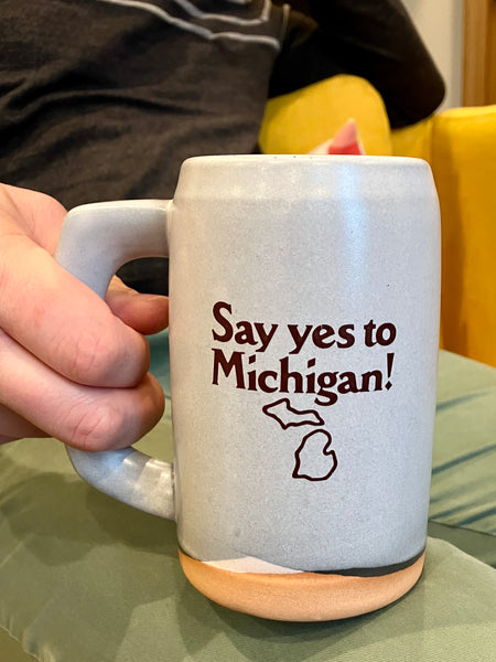 A gray ceramic stein with the logo for Say yes to Michigan! imprinted on the front. 