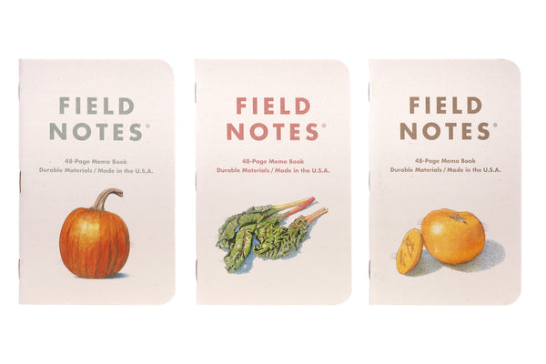 Three Field Notes Harvest notebooks which feature a pumpkin, Swiss chard, and a yellow tomato.