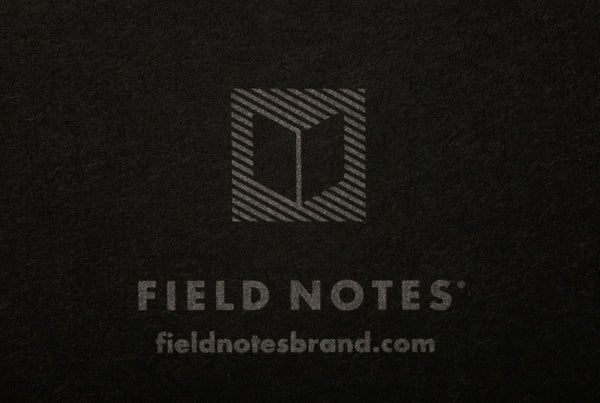 Close-up of Field Notes logo stamped in silver on the back of the Field Notes Pitch Black notebook.