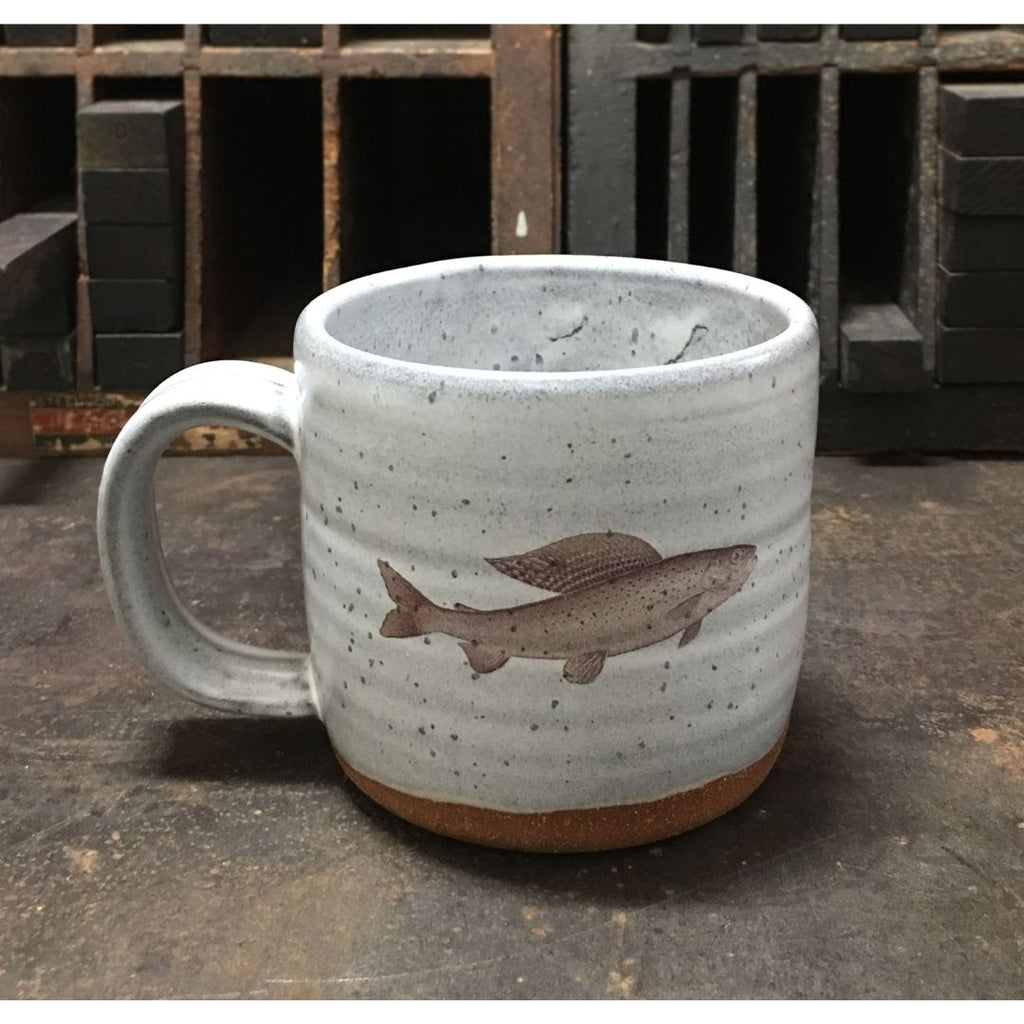 A gray ceramic mug with an image of a grayling imprinted on the front.