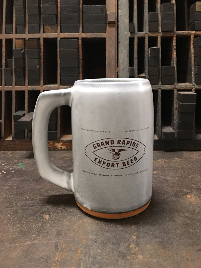 A light gray ceramic stein with the label for Grand Rapids Export Beer produced by Grand Rapids Brewing Company imprinted on the front. 