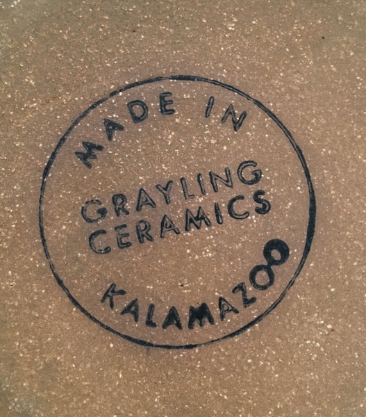 Close-up of underside of mug. A circular black ink stamp that reads “Grayling Ceramics Made in Kalamazoo”