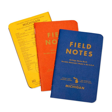 Three Field Notes notebooks in the County Fair pack. One is blue, one is orange, one is yellow.