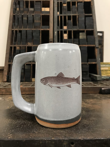 A light gray ceramic stein with an image of a brook trout imprinted on the front. 